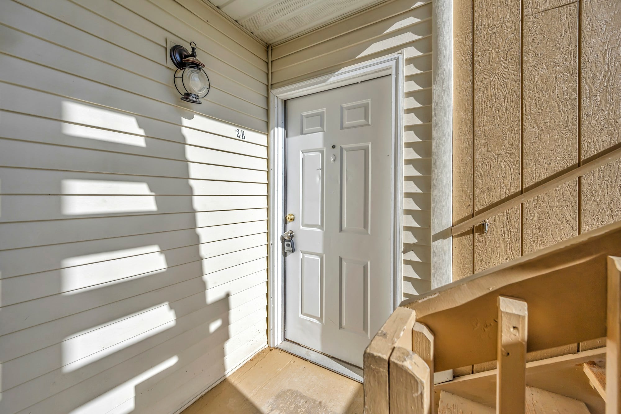 A residential front door and wooden porch railing
