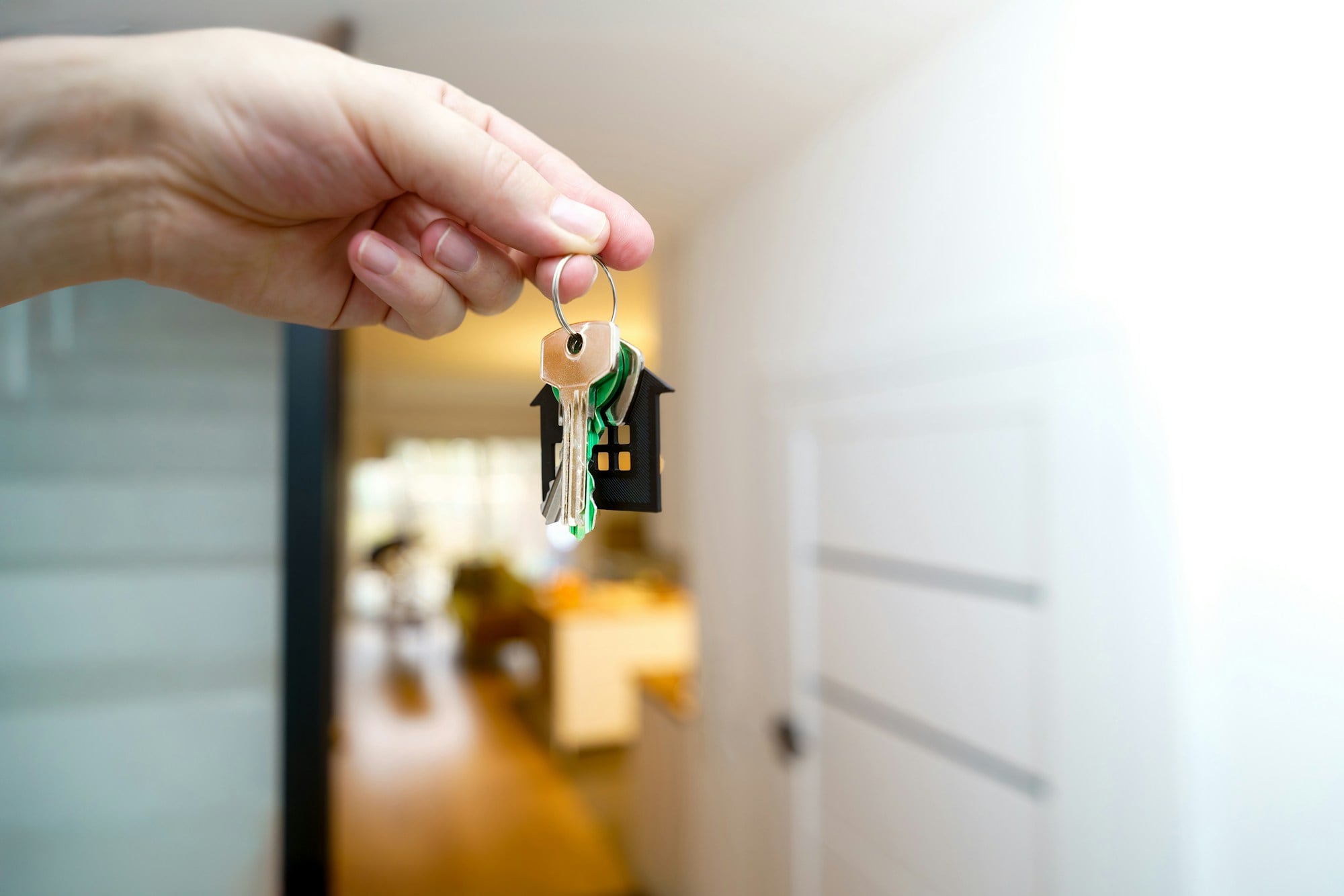 A hand holding house keys in front of a doorway