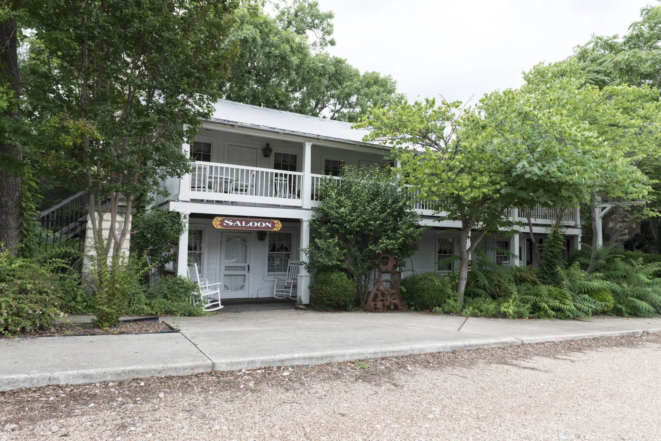 The historic Stagecoach Inn and its white porches framed by leafy trees in Salado, Texas